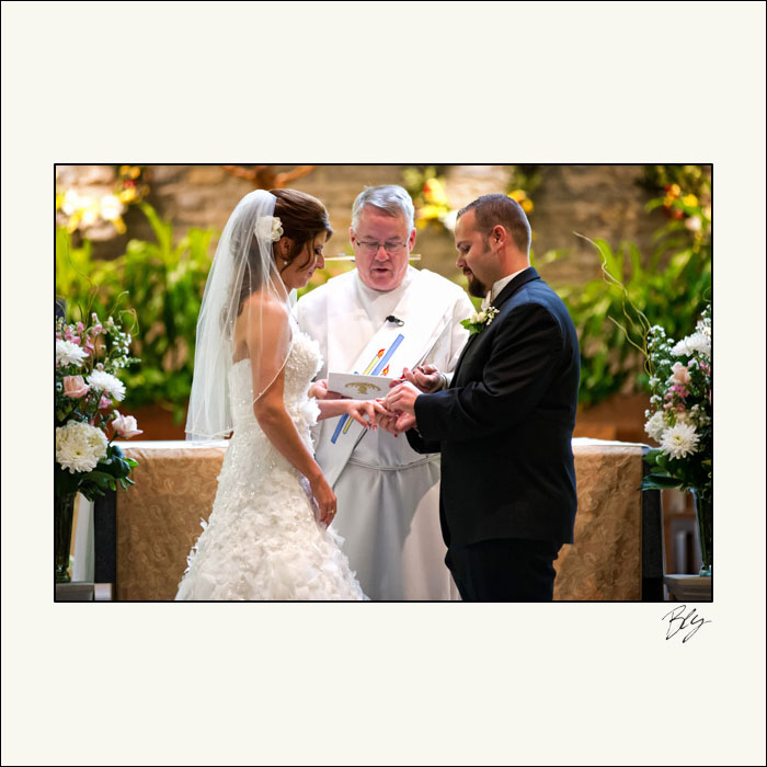 groom-putting-ring-on-bride-st-brendan-church-ceremony-hilliard-ohio-bly-photography